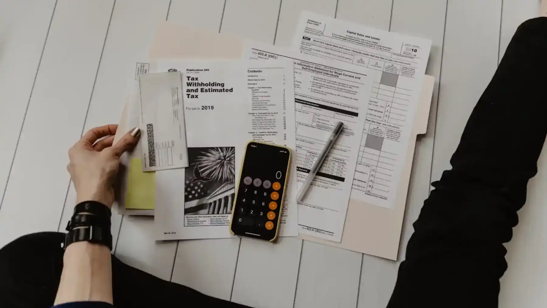 personne tenant du papier près d'un stylo et d'une calculatrice