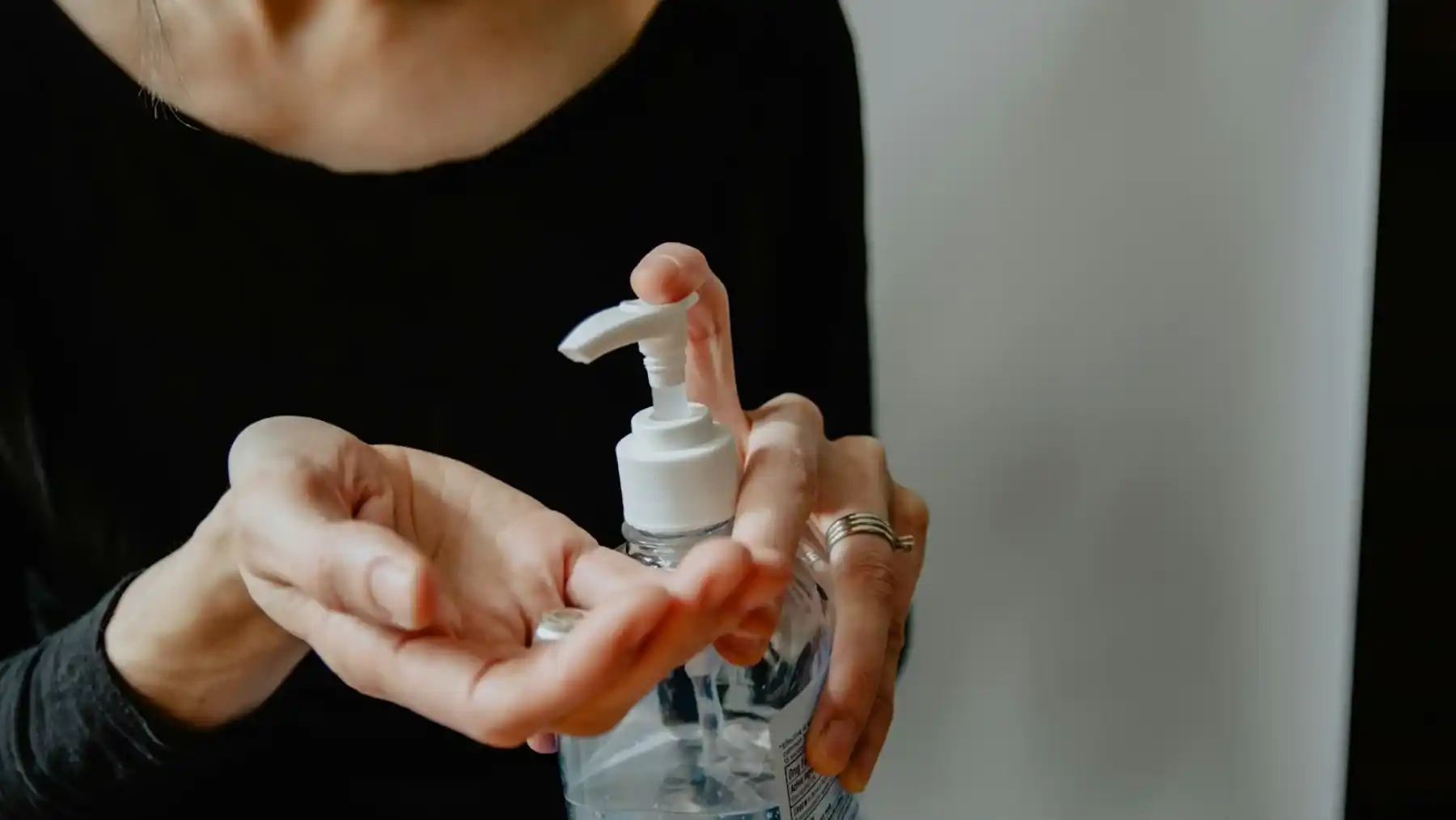 Femme en chemise noire tenant une bouteille en plastique blanche