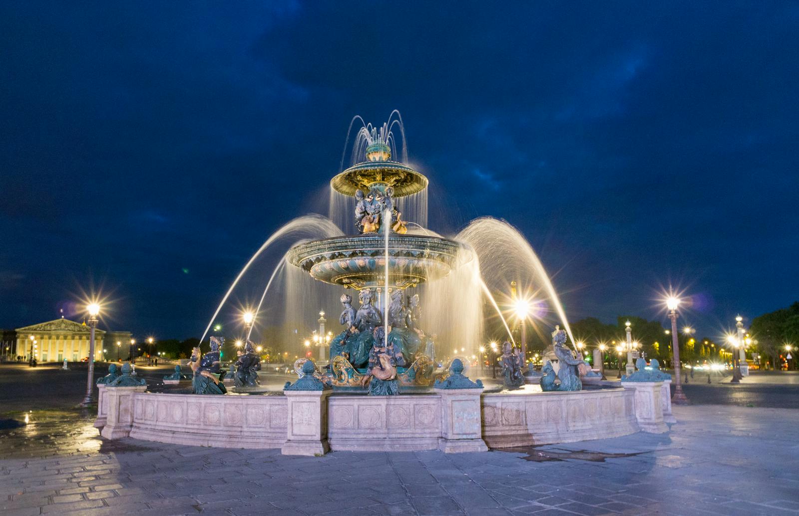 Lit-up view of Fontaine des Mers at Place de la Concorde, Paris at night.