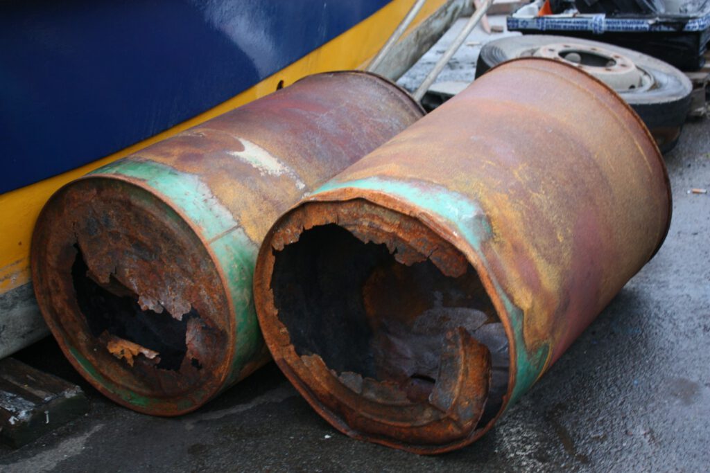 a couple of rusty pipes sitting next to a boat